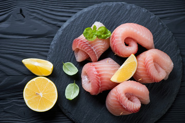Above view of marinated tilapia fish served in rolls on a stone slate tray