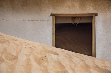 sand dunes over taking a house near Dubai