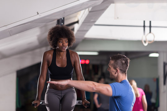 black woman doing parallel bars Exercise with trainer