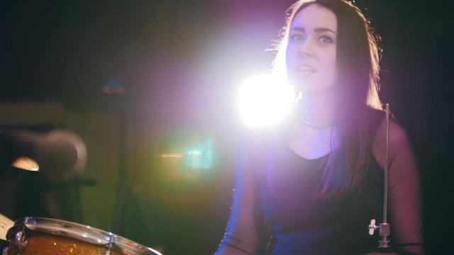 Dashing girl drummer with black hair at garage - rock band