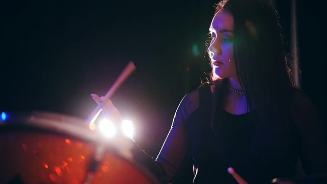Cute young woman plays with drumstick - drum performing, rock music, slow motion