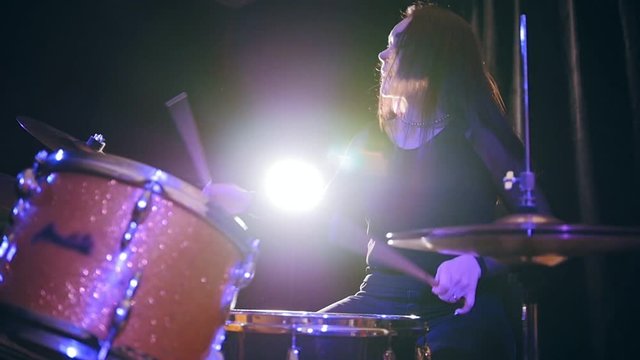 Rock girl percussion drummer performing with drums, slow motion