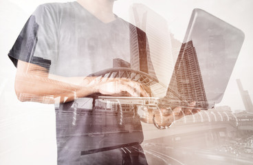 Double exposure of success businessman using labtop with with city landscape background