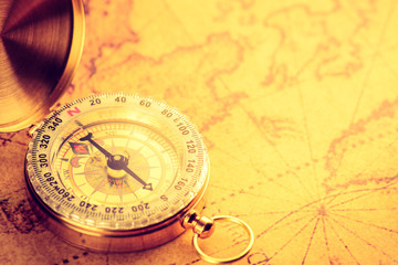 Fototapeta na wymiar Old gold vintage compass on vintage map:Heading south