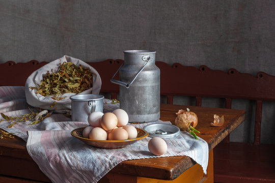 Still life. Country style. Aluminium utensils, bag with flowers of linden and eggs on a wooden table. Natural lighting.