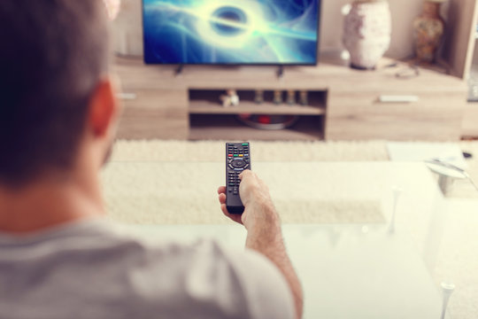Man with remote control watching sci-fi at home in TV