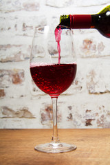Glass of full bodied red wine being poured