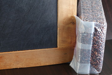 The slate board and rice berry put on wooden style background represent the raw food material concept related idea.