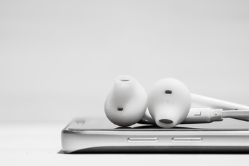 White earphone on smart phone while playing music, video clip or podcast and movie.