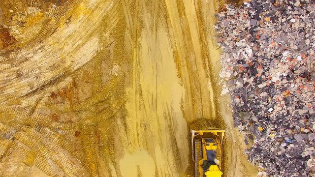 Aerial view of bulldozer on muddy construction site or dump. Heavy industry from above. Industrial background from devastated landscape.