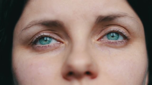 Green-eyed female face looks away and up to the camera. close-up view with sad girl