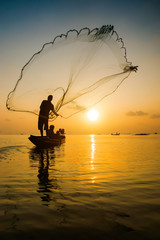 Silhouettes fisherman throwing fishing nets during sunset, Thailand.