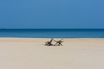 Fototapeta na wymiar An empty white sand beach with drift wood decoration and calm sea.