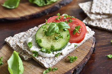 Healthy eating or dieting scene with crisp bread and fresh tomatoes and cucumber. Wooden table, rustic scene.