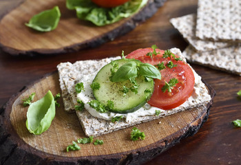 Healthy eating or dieting scene with crisp bread and fresh tomatoes and cucumber. Wooden table, rustic scene.