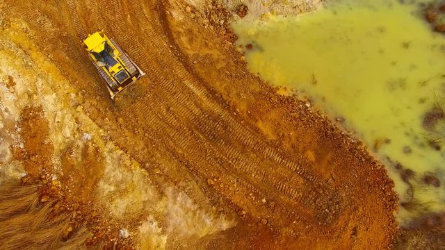 Aerial view of bulldozer on muddy construction site or dump. Heavy industry from above. Industrial background from devastated landscape.