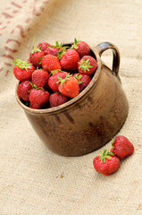 Ceramic pot full of fresh red strawberries on canvas