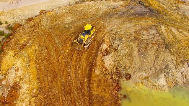 Aerial view of bulldozer on muddy construction site or dump. Heavy industry from above. Industrial background from devastated landscape.