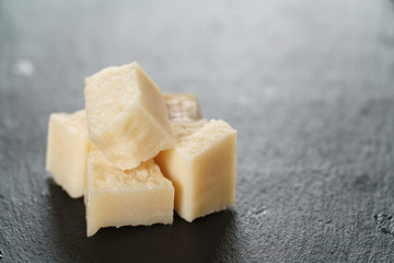 pieces of hard parmesan cheese on slate board, closeup photo