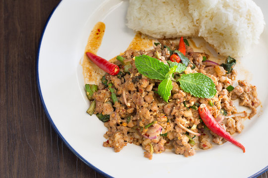 Ground pork salad with sticky rice and fresh vegetable Thai food and Thai called “Larb” on dark wooden table / Selective focus Image

