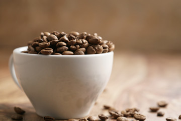 cappuccino cup with roasted coffee beans on wood table, with copy space