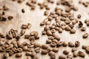 roasted coffee beans falling on wood table, shallow focus