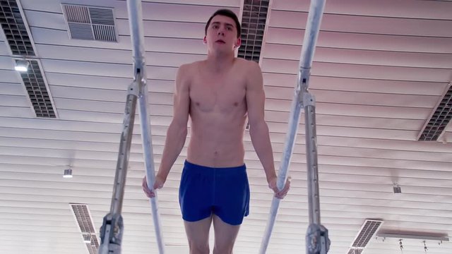 Gymnast performs routine on parallel bars HD gymnastics slow-motion video. Olympics athlete training skills and doing swings acrobatic exercises: handstand
