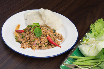 Ground pork salad with sticky rice and fresh vegetable Thai food and Thai called “Larb” on dark wooden table / Selective focus Image
