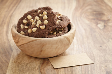 homemade chocolate cookies with chocolate chips and hazelnuts with empty paper card, shallow focus