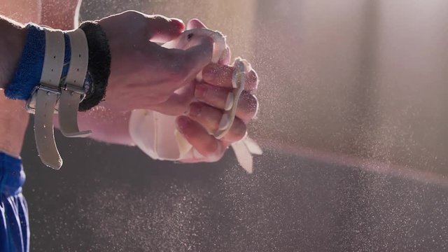 Athlete chalking hands wearing gymnastic grips before training HD slow-motion video. Close-up view of gymnast hand