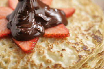 premium dark chocolate poured on blinis with strawberry, shallow focus