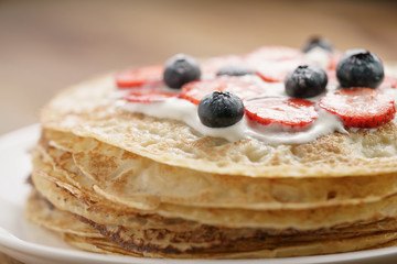 fresh blinis or crepes with fresh berries and cream, closeup shot