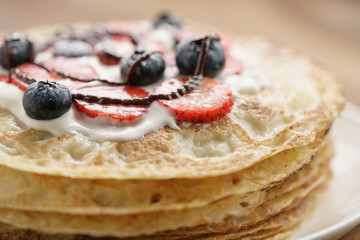 fresh blinis or crepes with fresh berries and cream decorated with chocolate sauce, closeup photo