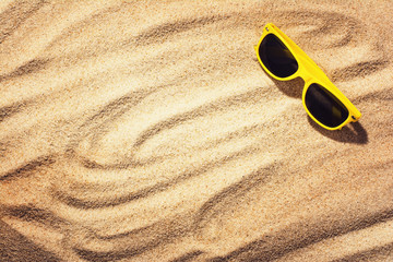 Sunglasses on a sandy beach background. Top view with copy space around product. Travel or vacation and sunbathing concept image.