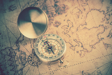 Old  gold vintage compass on vintage map:Heading south;vintage tone style