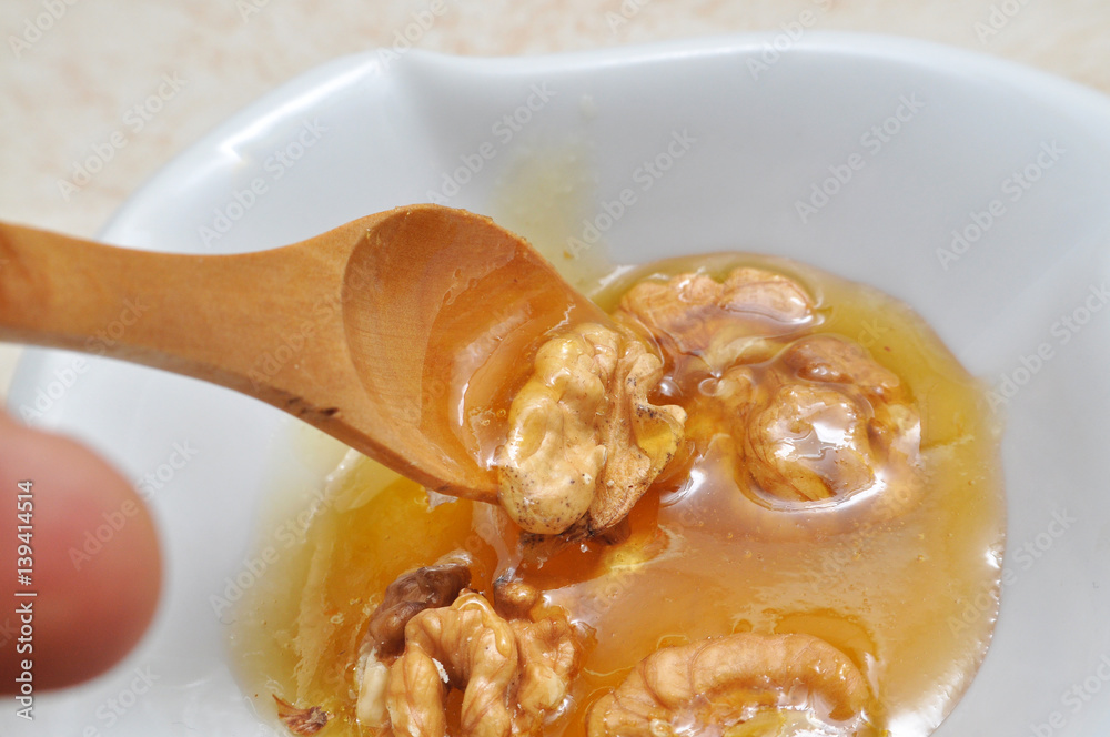 Wall mural Mixture of honey and walnuts eaten by wooden spoon. Healthiest mixture