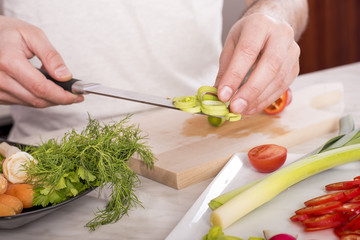Close up of man in the kitchen while preparing fresh vegetable salad