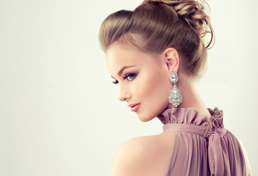 Beautiful girl with elegant hairstyle and big earrings jewelry .

