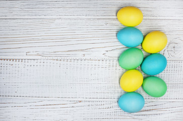Colored eggs on a white wooden background. Concept Happy Easter.