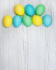 White wooden background with colored eggs for greeting. Concept Happy Easter.