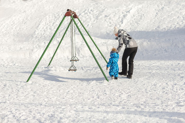 Young mother walking with her son in the Park in winter on a Sunny day