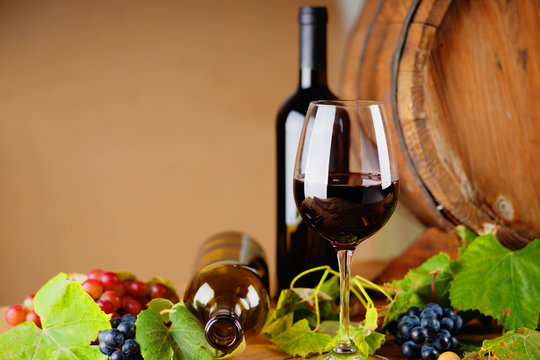 Wine bottles, glass, grapes and barrel 