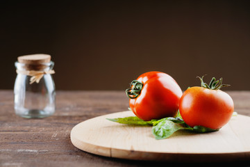 Tomatoes on a cutting board and empty glass jar