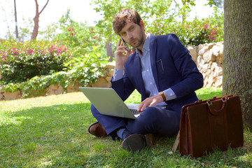 Serious business man on the phone while working with pc in park