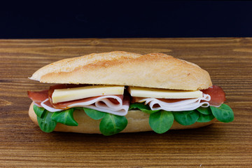 Fresh sandwich whit salad, bacon and cheese on wood 