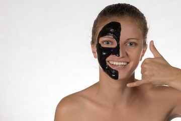 Happy beautiful girl with acne on a white background in a cosmetic mask black