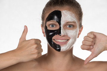 Happy beautiful girl smiling on a white background in a cosmetic mask of black and white color