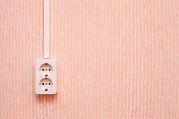 white socket on a wall with wallpaper