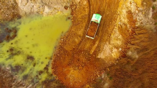 Aerial view of truck riding on muddy road trough a dump. Heavy industry from above. Industrial footage from devastated landscape. 