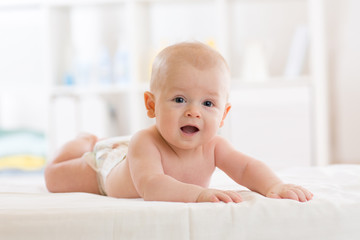 Portrait of a three months old baby boy on bed in nursery room